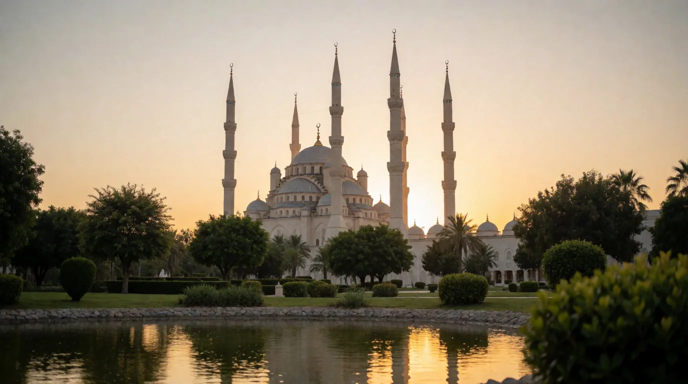 Ağaçlar, çalılar ve su yansıması önünde yükselen kubbeli cami silueti gün batımı ışığında görünüyor