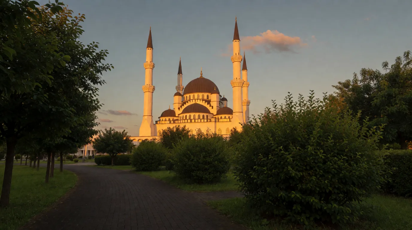 Ağaçlar ve çalıların arasından görünen, akşam ışığında parlayan kubbeli cami ve minareler