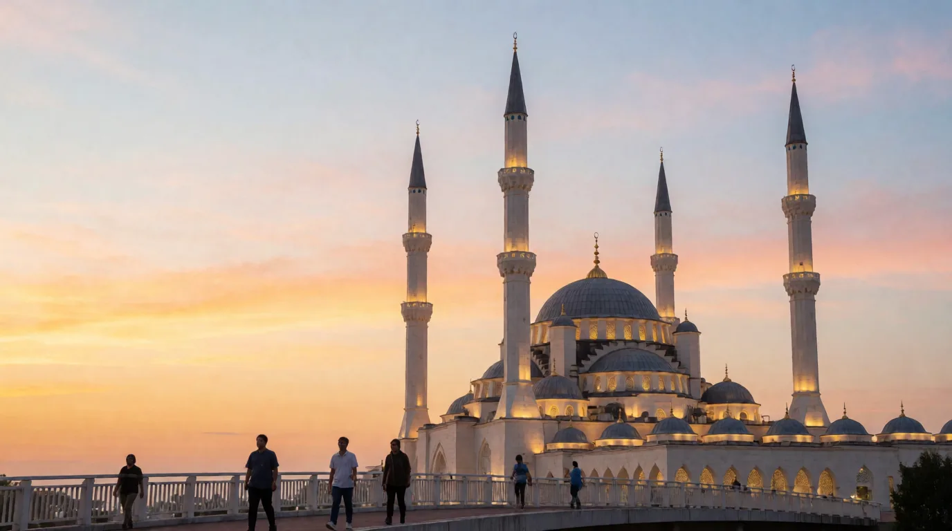 Gün batımında dört minareli bir cami silüeti, önünde yürüyen birkaç kişi ve açık renkli gökyüzü